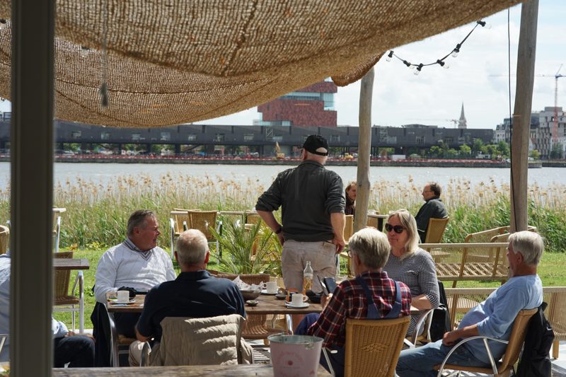 Gasten op het terras van Liberty bij avondlicht, met de Schelde op de achtergrond